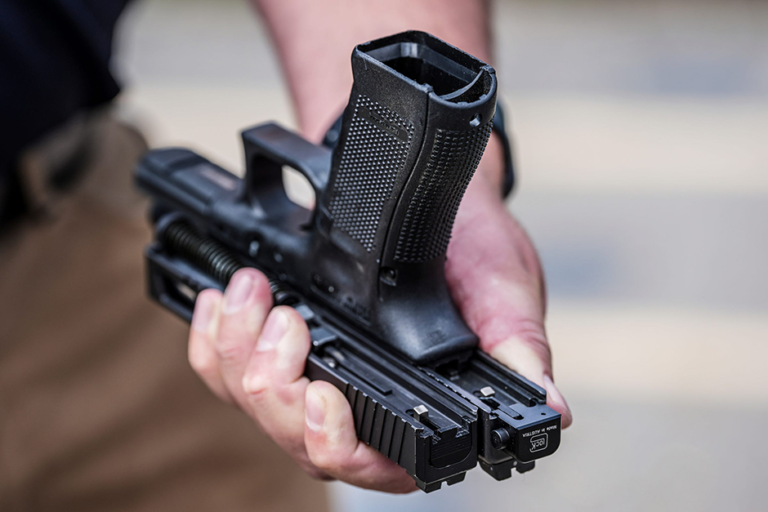 Special Agent Kenton Weston holding two Glock handgun slides, one with a machine gun conversion switch, right, and one without, during a demonstration at the Canton Police Department training facility in Canton, Ohio.